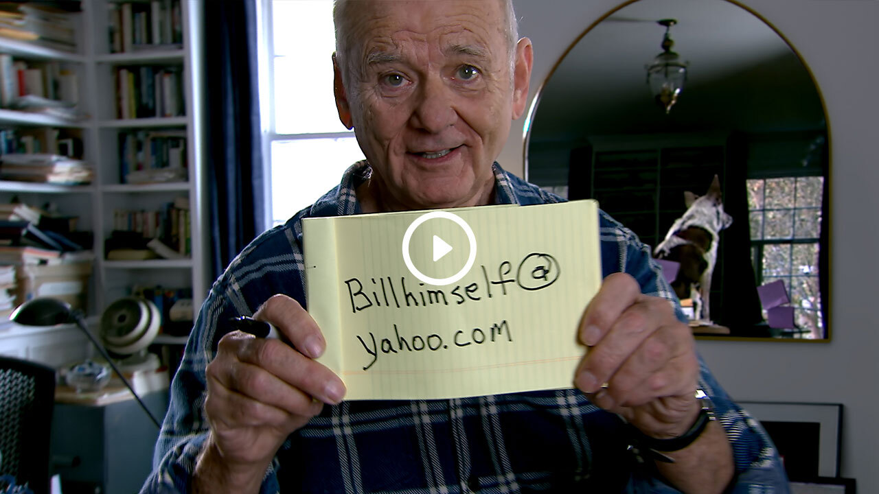 Picture of Bill Murray holding a yellow legal pad that reads 'Billhimself@yahoo.com' with a play button imposed on top of it. - PNG